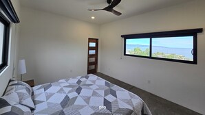 Ein Schlafzimmer mit Bett, Deckenventilator, Fenster mit Aussicht und einer Tür.
