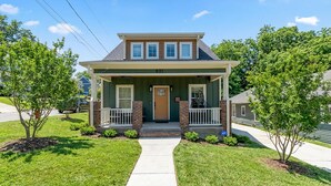 A two-story house with a front porch, a front door, and a small driveway. - King Bed | EV Charger | 12 Guests | Modern (Durham)