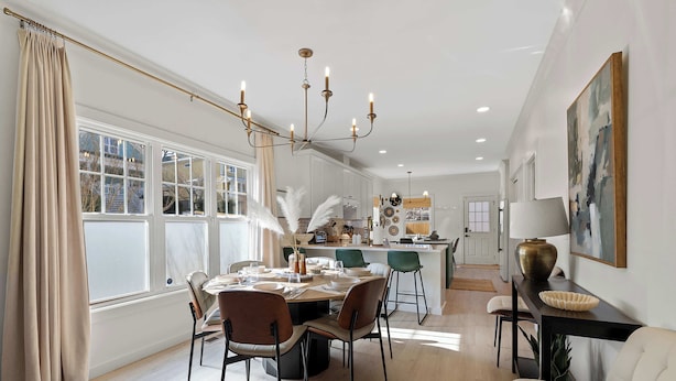 A dining area with a table set for four, a chandelier, and a view of the kitchen. - King Bed | EV Charger | 12 Guests | Modern (Durham)