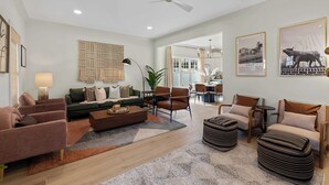 A spacious living room with a sofa set, a coffee table, and a dining area with chairs and a table. - King Bed | EV Charger | 12 Guests | Modern (Durham)