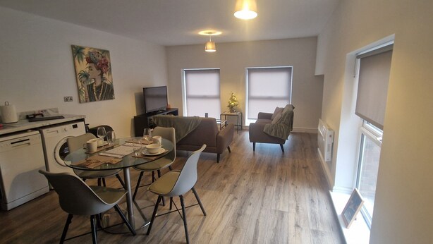 A compact living space with a dining area, kitchenette, and a seating area with a TV. - Sarah's Woodland Golf Stays (Waterloo)