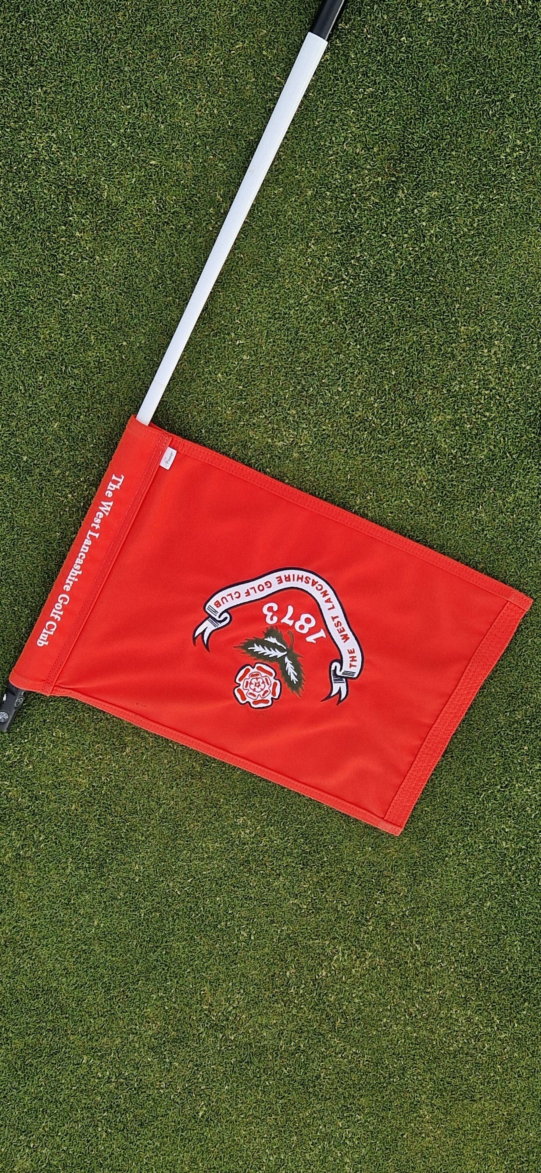 Un drapeau rouge avec du texte blanc et un logo sur un fond vert.