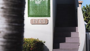 Entrada de un edificio con un cartel que dice 'IGUANA HOTEL' y el número '1700' debajo.