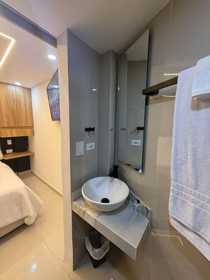 A modern bathroom with a round sink, a mirror, and a towel rack. - SkyGlow Suite | Luxury Queen + Rooftop Access (Cartagena de Indias)