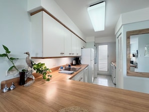 Eine moderne Küche mit weißen Schränken, einer Holz Arbeitsplatte, einem Spülbecken und einem Kühlschrank.