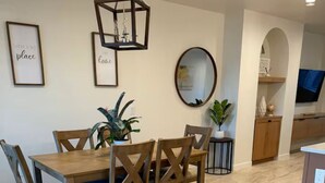 A dining area with a wooden table and chairs, a hanging light fixture, framed artwork on the wall, and a mirror. - Entire Home/Gated/King On suite (Tucson)