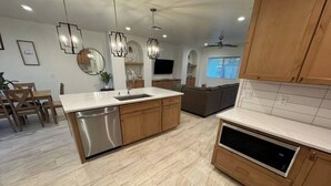 A modern kitchen with a dishwasher, built-in oven, and wooden cabinets. - Entire Home/Gated/King On suite (Tucson)