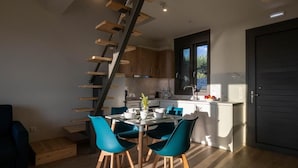 Una cocina moderna con una isla central, una escalera de madera y sillas color turquesa.