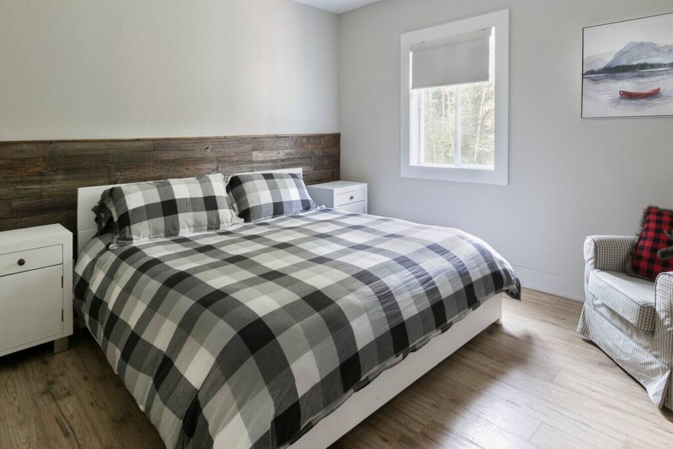 A bedroom with a bed, nightstands, a window, and a painting on the wall.