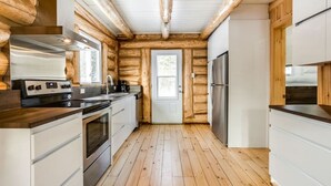 A modern kitchen with wooden walls, stainless steel appliances, and a wooden floor. - Avec accès au Petit lac Long (Saint-Adolphe-d`Howard)