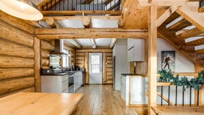 A wooden cabin interior with a kitchen, dining area, and a staircase. - Avec accès au Petit lac Long (Saint-Adolphe-d`Howard)