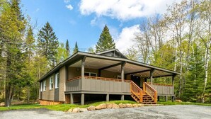 Een chalet met twee verdiepingen, een overdekte veranda en een trap naar de bovenverdieping.