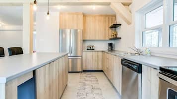 Une cuisine moderne avec des meubles en bois, des appareils électroménagers en acier inoxydable et une grande fenêtre.