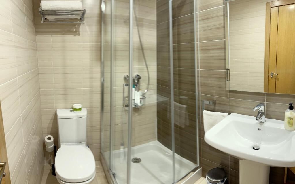Un baño moderno con cabina de ducha de vidrio, inodoro y lavabo con espejo.