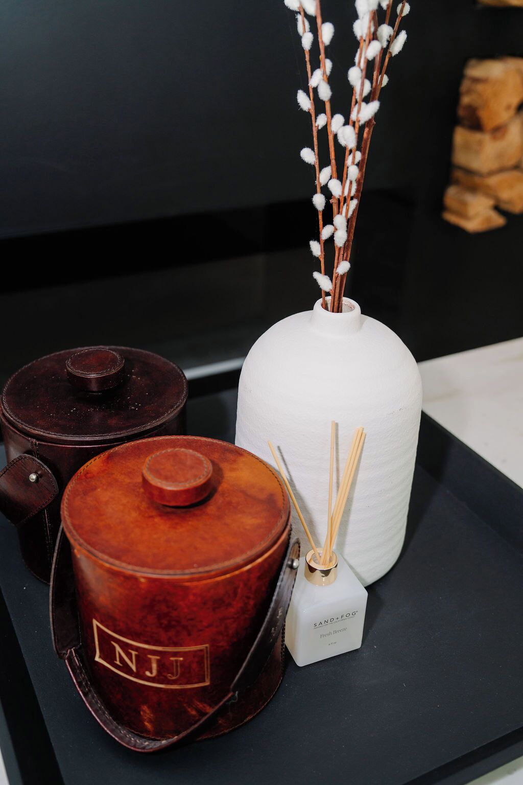 A display of three containers with lids, one white and two brown, on a black surface.