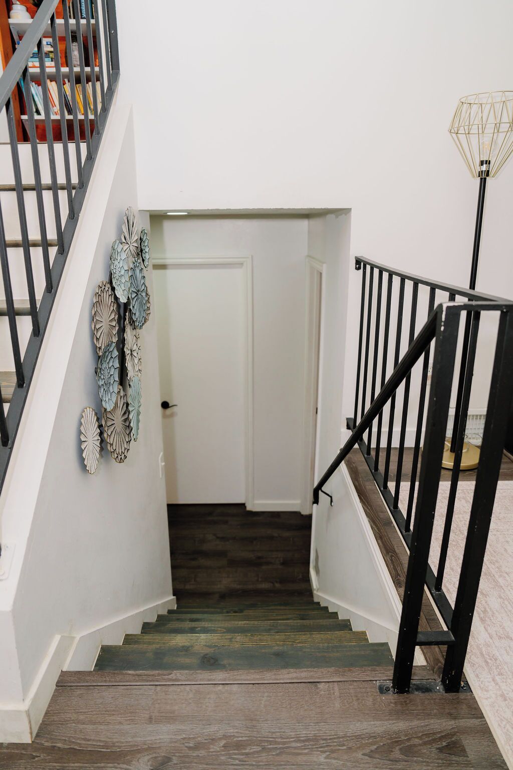 A staircase with wooden steps and black railings, leading to a white door.