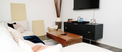 A modern living room with a sofa, coffee table, and a flat-screen TV mounted on the wall.