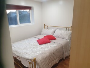 A single bed with a headboard, a window with a view of a fence, and a wooden floor. - Beautiful 2-bedroom basment house with your own entrance (Sandy)