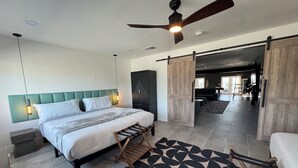 Ein modernes Schlafzimmer mit Bett, Deckenventilator, großem Kleiderschrank und Blick in einen Essbereich.