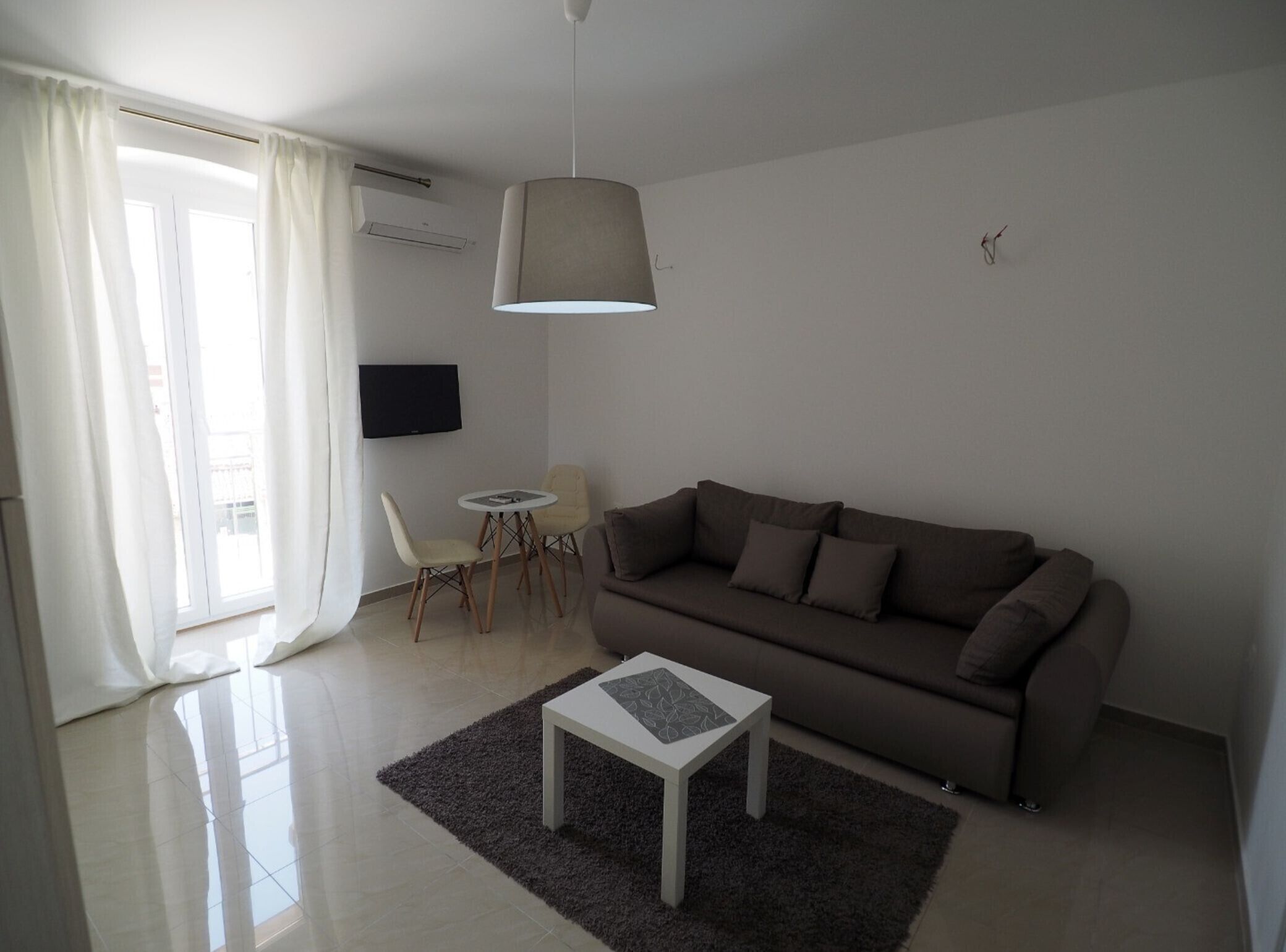 A modern living room with a sofa, a small table, and a TV mounted on the wall.