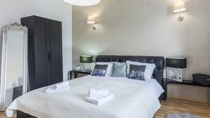 A modern bedroom with a large bed, two bedside lamps, a wardrobe, and a mirror. - Comfrot One Bedroom Apartment with Sea View (Pula)