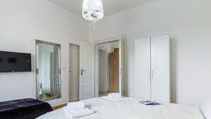 Une chambre à coucher avec un grand lit, une télévision, une armoire et un lustre.
