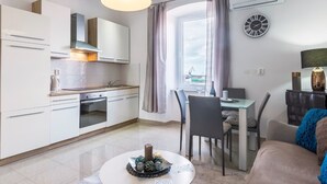 Une cuisine moderne avec des meubles blancs, un four encastré et un coin repas comprenant une table et des chaises.