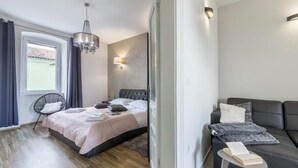 Een moderne slaapkamer met een bed, een stoel, een bank, een leestafel en een kroonluchter.