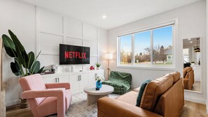 Un salon moderne doté d’un téléviseur à écran plat, de sièges confortables, d’une grande fenêtre et d’une vue sur l’extérieur.