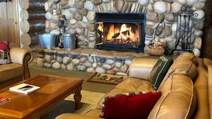 A cozy living room with a stone fireplace, leather sofa, and a coffee table. - Hebgen Paradise Lodge (West Yellowstone)
