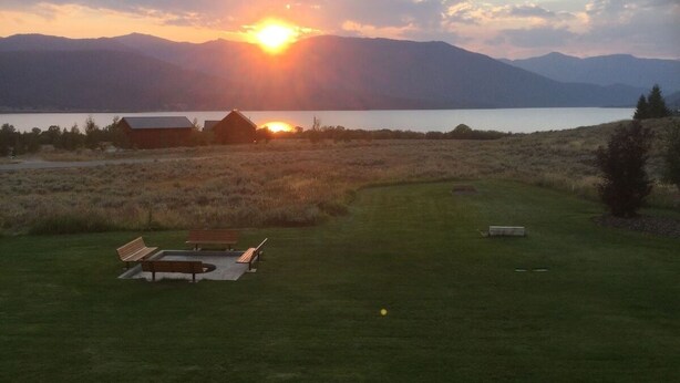 A lakeside view with a sunset, a wooden bench, and a small building. - Hebgen Paradise Lodge (West Yellowstone)