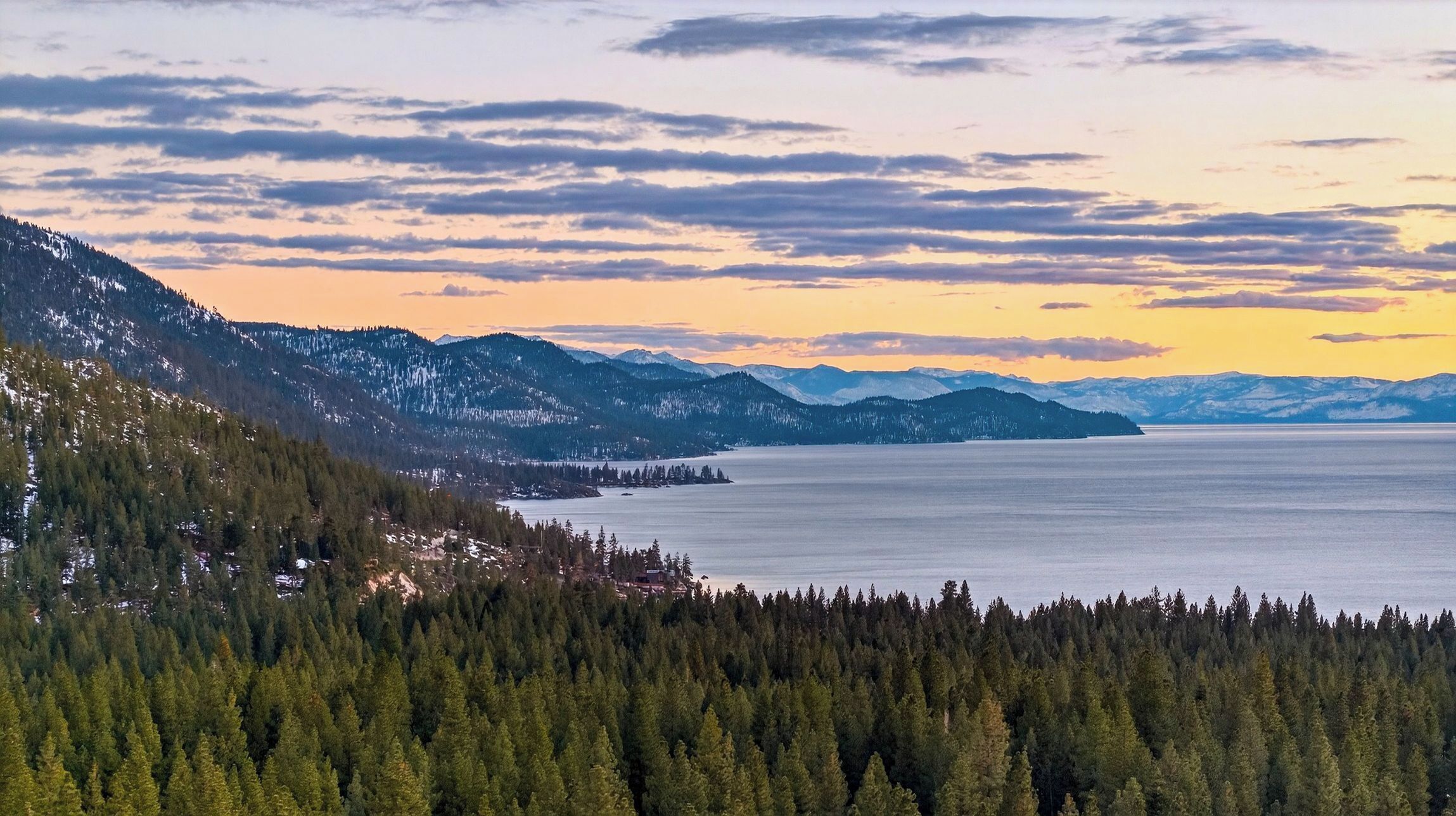 A mountainous landscape with a lake and dense forest.