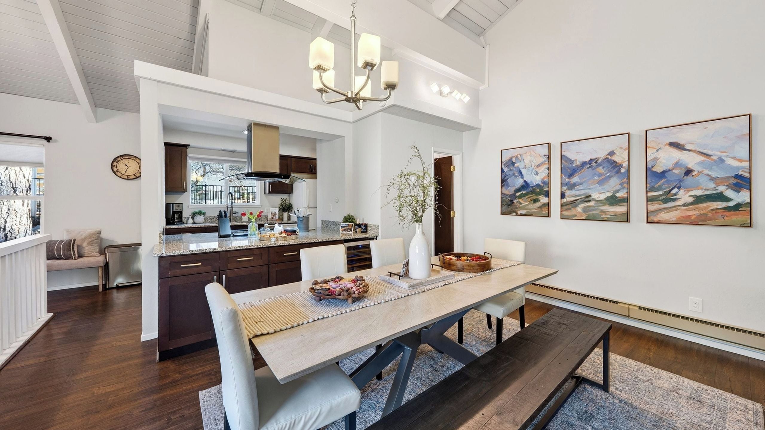 Een moderne keuken met donkerhouten kastjes, een centraal eiland en een eethoek met een houten tafel en stoelen.