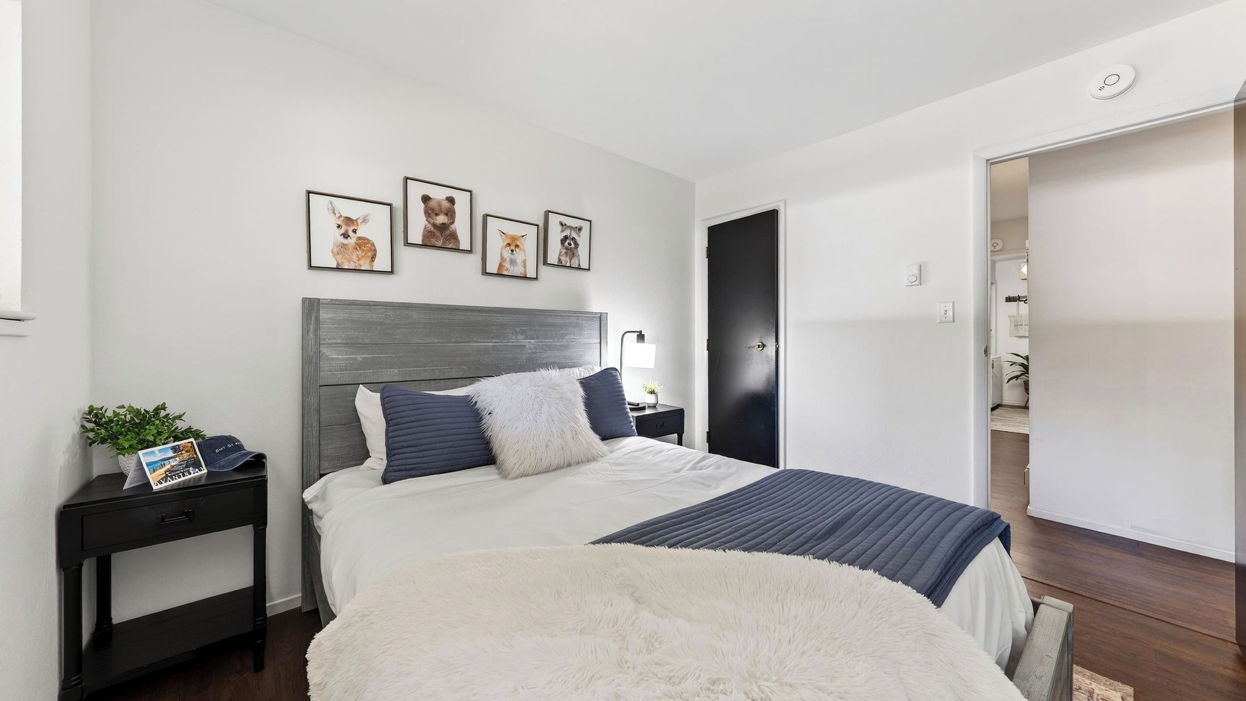Ein Schlafzimmer mit Bett, Nachttischen und einer Wand mit gerahmten Bildern.