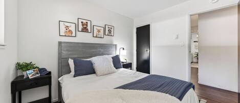 Ein Schlafzimmer mit Bett, Nachttischen und einer Wand mit gerahmten Bildern.