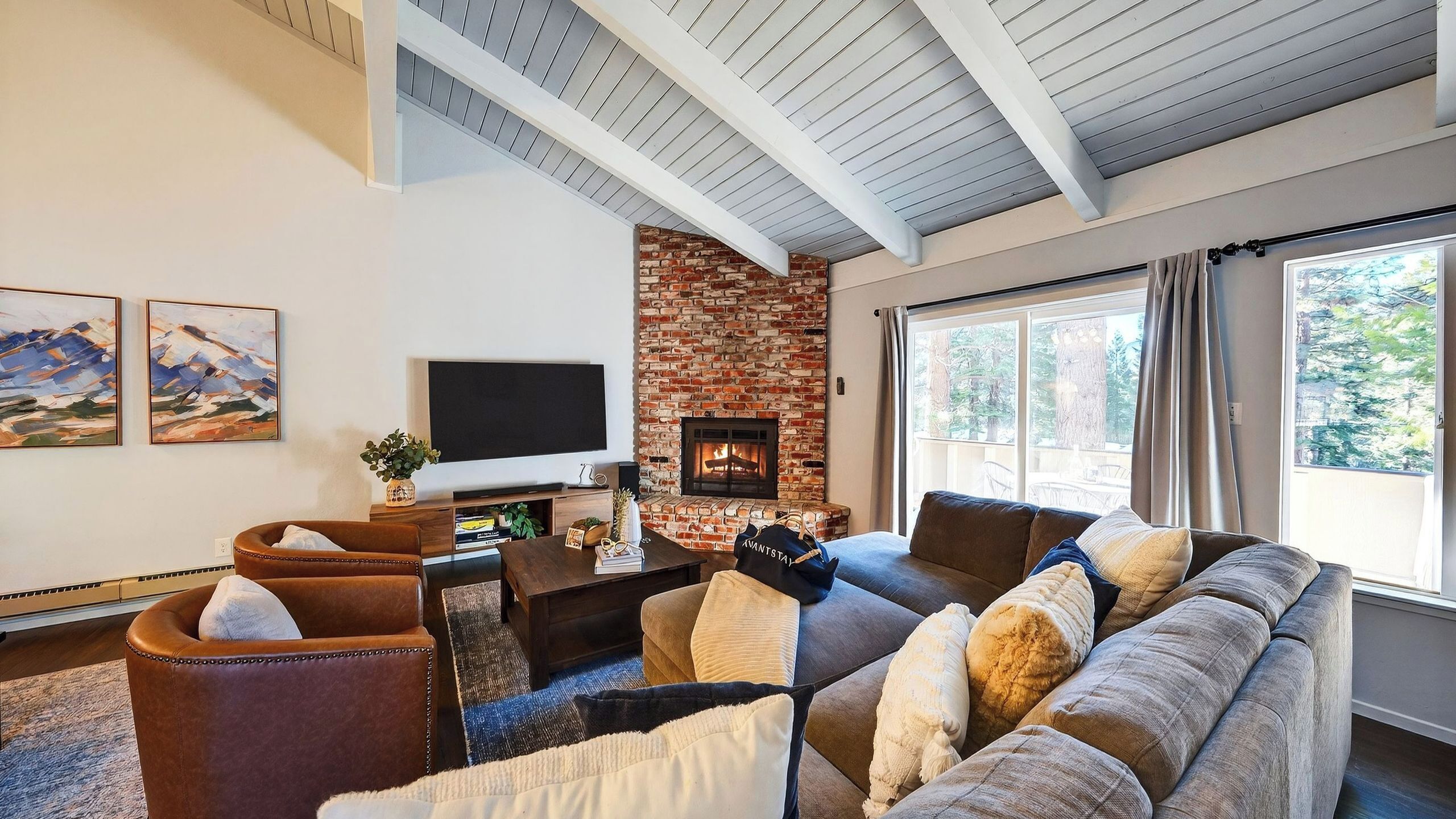 A living room with a brick fireplace, a large window, and a sofa.