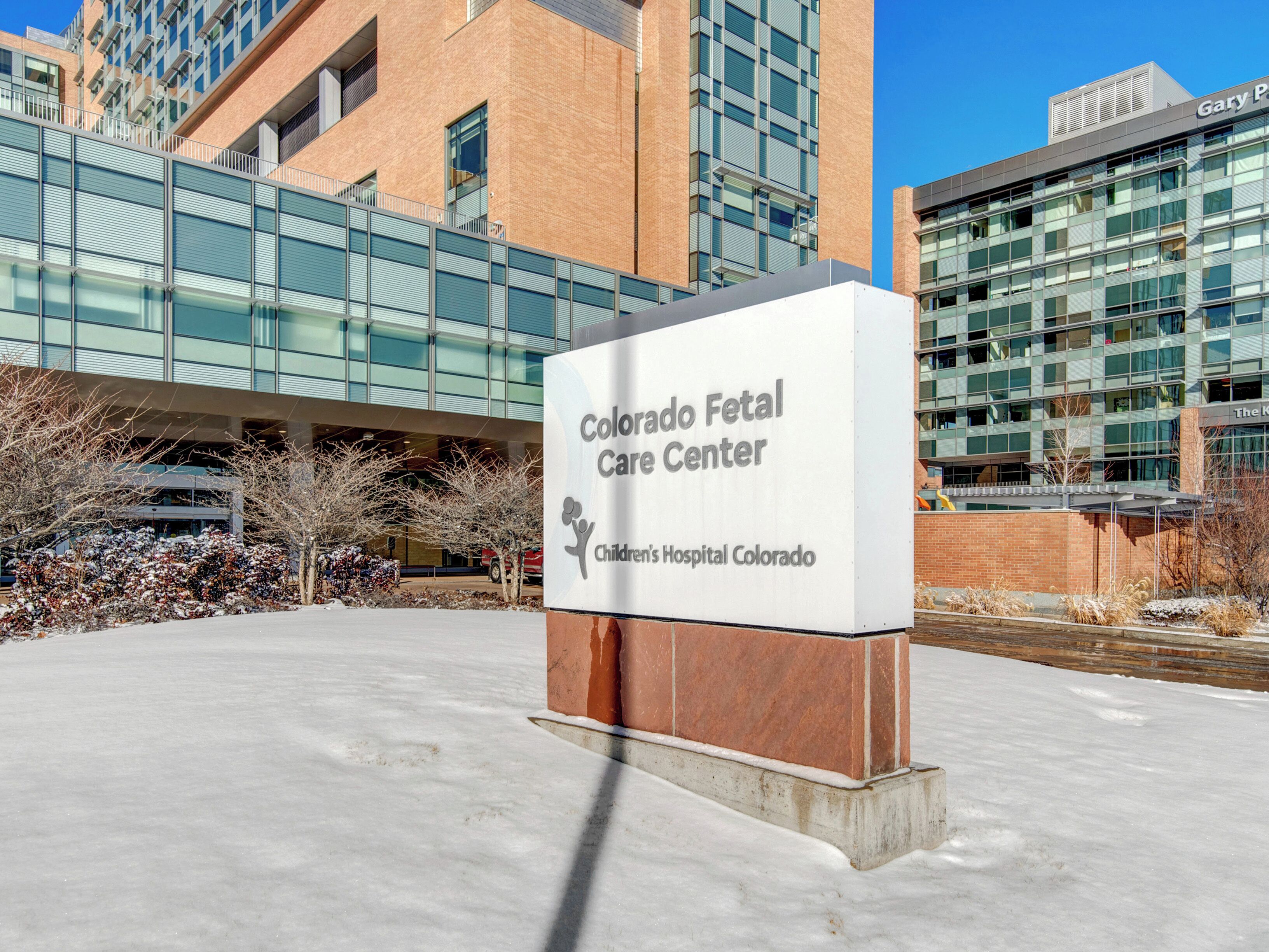 Une enseigne indiquant le «Colorado Fetal Care Center», avec un bâtiment moderne en arrière-plan.