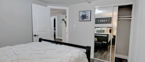 Quarto com cama, armário e banheiro visível por uma porta aberta.