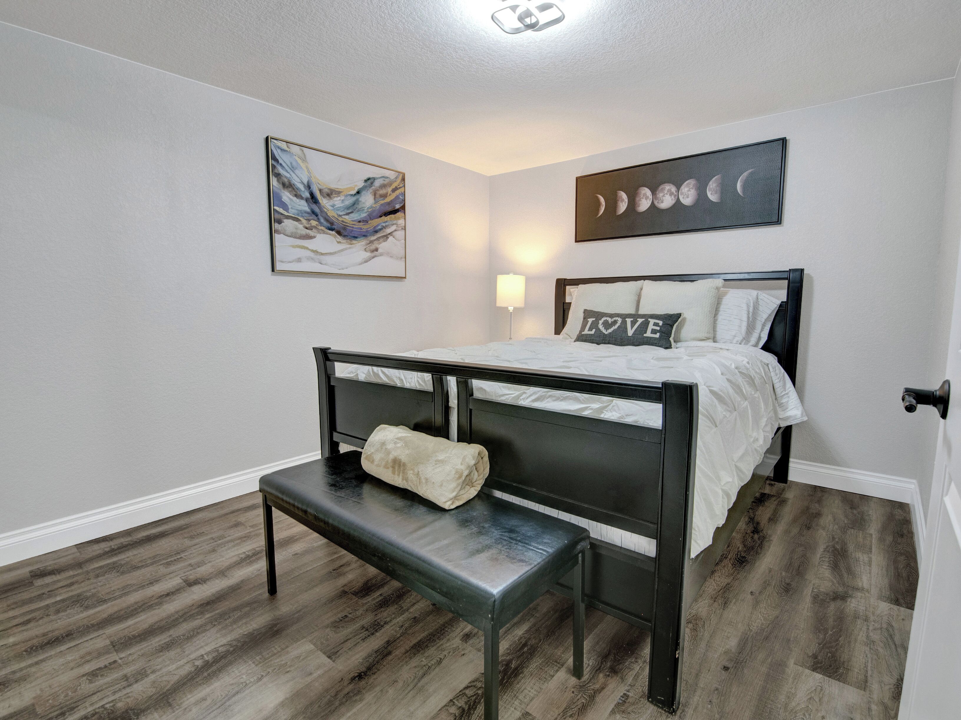 Un dormitorio con cama, banqueta, obra de arte y decoración de fases lunares.