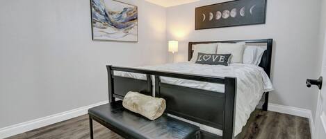 Un dormitorio con cama, banqueta, obra de arte y decoración de fases lunares.