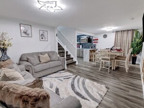 A modern living room with a grey sofa, a patterned rug, and a dining area with wooden chairs and a table. - 3-bed/1 bath basement apartment in Aurora, CO w/AC~close to Hospitals (Aurora)