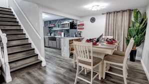 Eine moderne Küche mit Marmor-Spritzschutz, Holzboden und einem Essbereich mit Tisch für vier Personen.