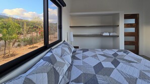 A bedroom with a large window, a bed with a geometric patterned bedspread, and built-in shelves. - 1 Bedroom 1 Bathroom Luxury La Ventana Villa w/ Ocean Views: (La Ventana)