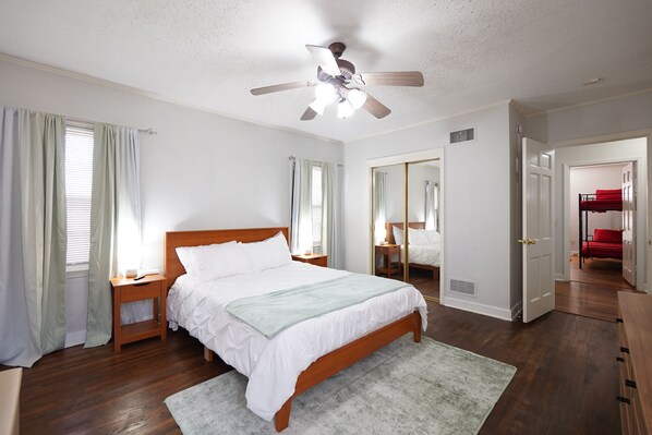 Un dormitorio con cama de madera, ventilador de techo y un espejo grande.