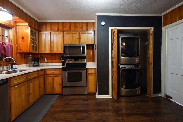 Una cocina con armarios de madera, electrodomésticos de acero inoxidable y una pared negra.