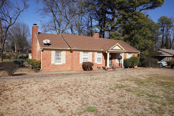 A single-story brick house with a chimney, satellite dish, and a front porch.