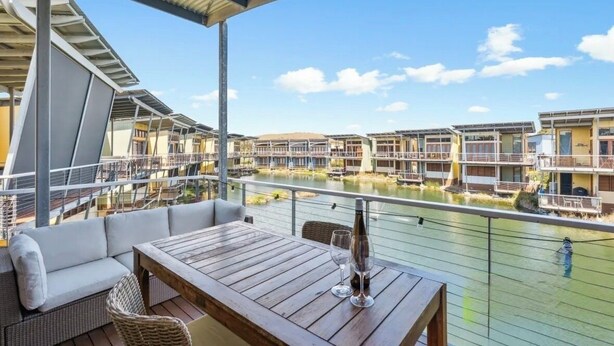 A covered outdoor seating area with a view of a canal and buildings.