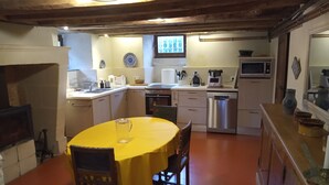 A kitchen with a yellow table, wooden chairs, a sink, a stove, and a microwave. - Between Angers, Le Mans and Saumur, a gîte in a château near the Loire. (Jarzé Villages)
