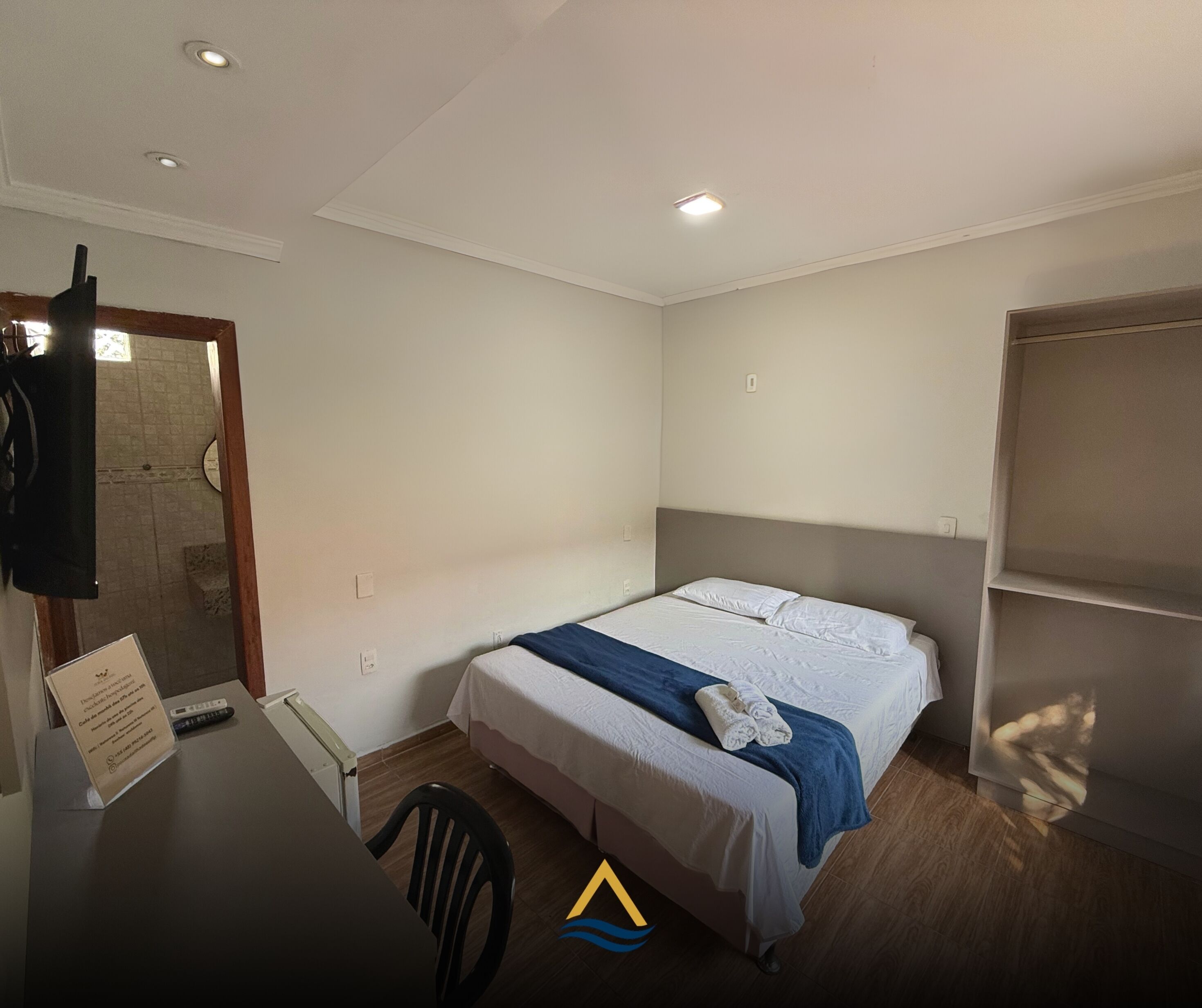 Une chambre d’hôtel comprenant un lit, un bureau avec une chaise, une armoire et un espace douche.