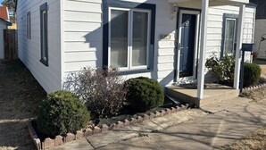 A single-story house with a front porch, a mailbox, and a small garden area. - My family’s little nest, where our kids grew. (Perryton)